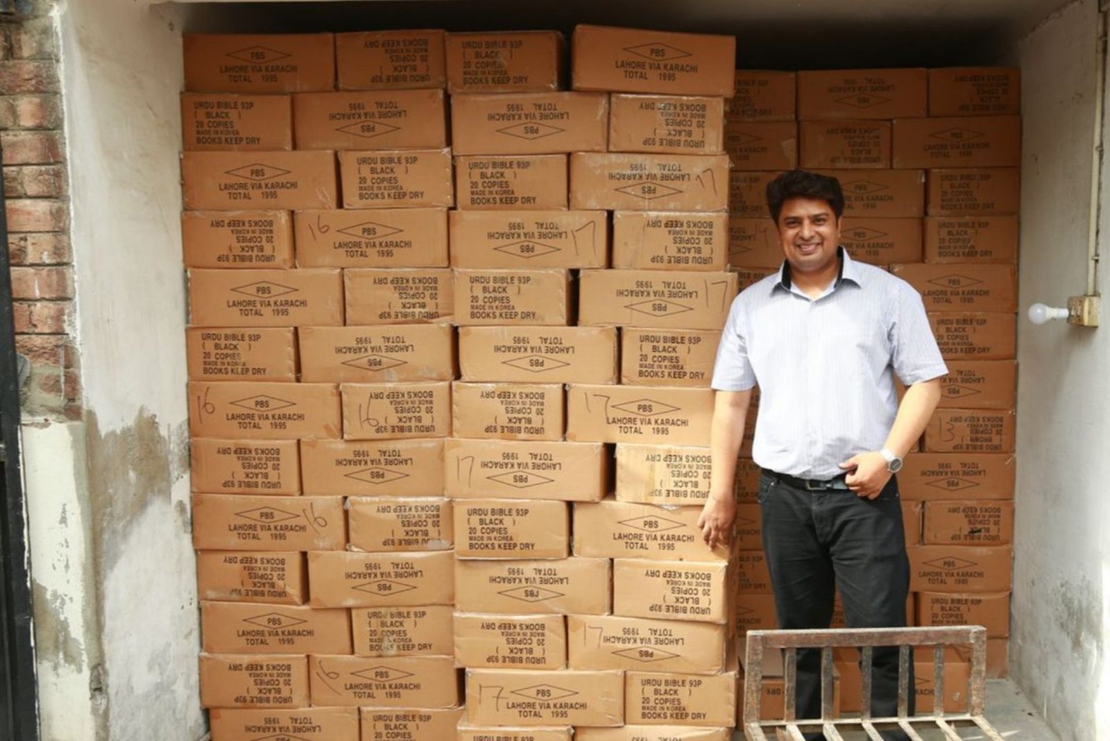 A ministry worker beside boxes of Urdu Bibles stacked in the store before a distribution in Pakistan