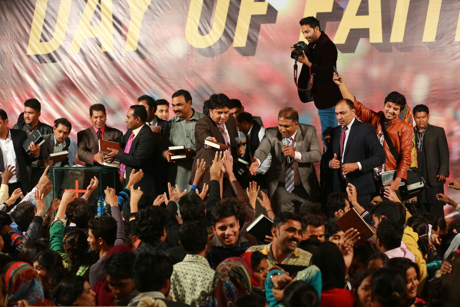 A crowd at a Day of Faith event in Pakistan holding up free Urdu Bibles