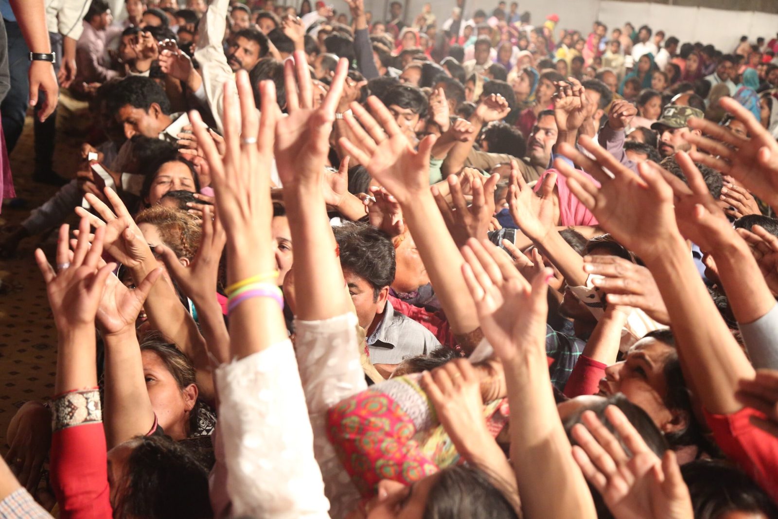 Hundreds of hands raised holding free Urdu Bibles at an evangelistic crusade in Pakistan