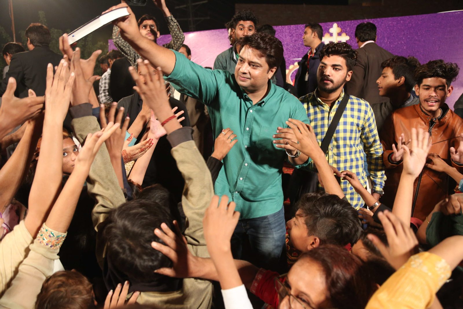 A crowd of believers in Pakistan reaching up to receive free Urdu Bibles at a Good Samaritan Ministries distribution