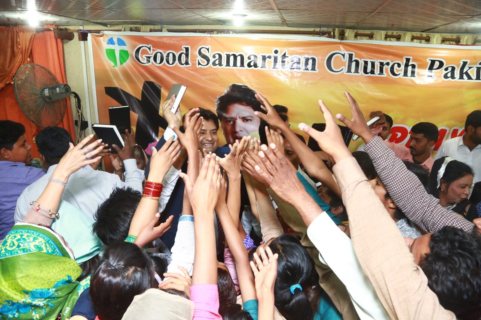 A packed crowd at Good Samaritan Church in Pakistan reaching for free Urdu Bibles