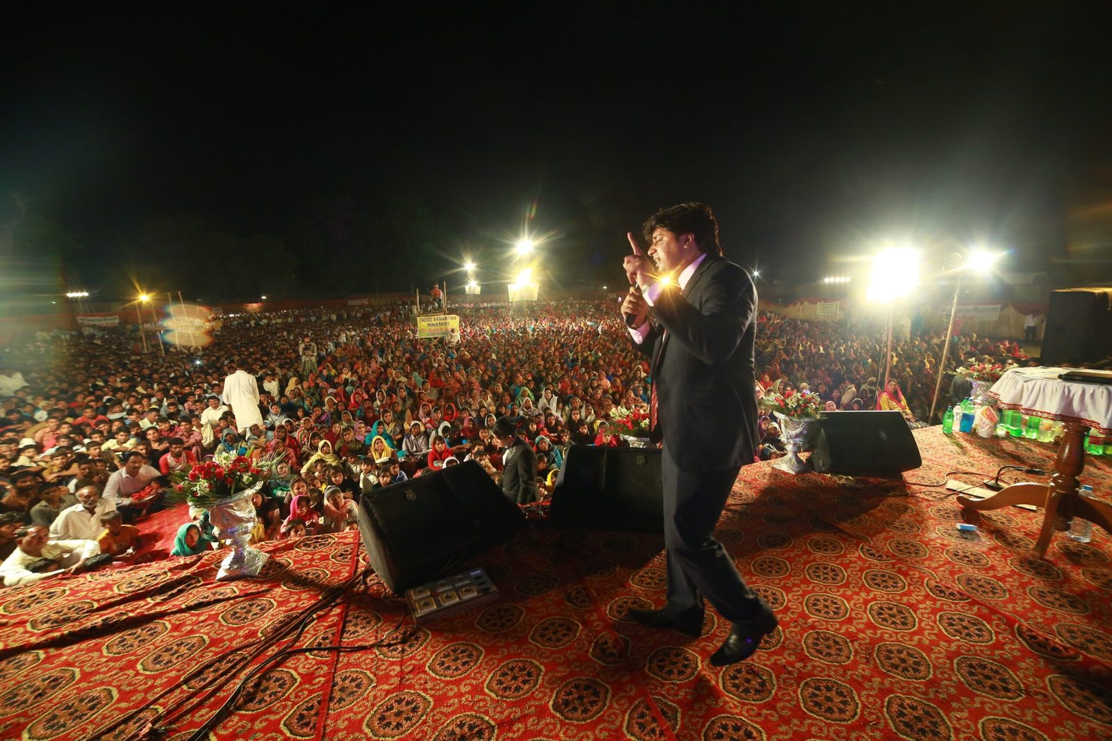 A night-time gospel revival crusade in Khanewal, Pakistan, with thousands seated on the ground