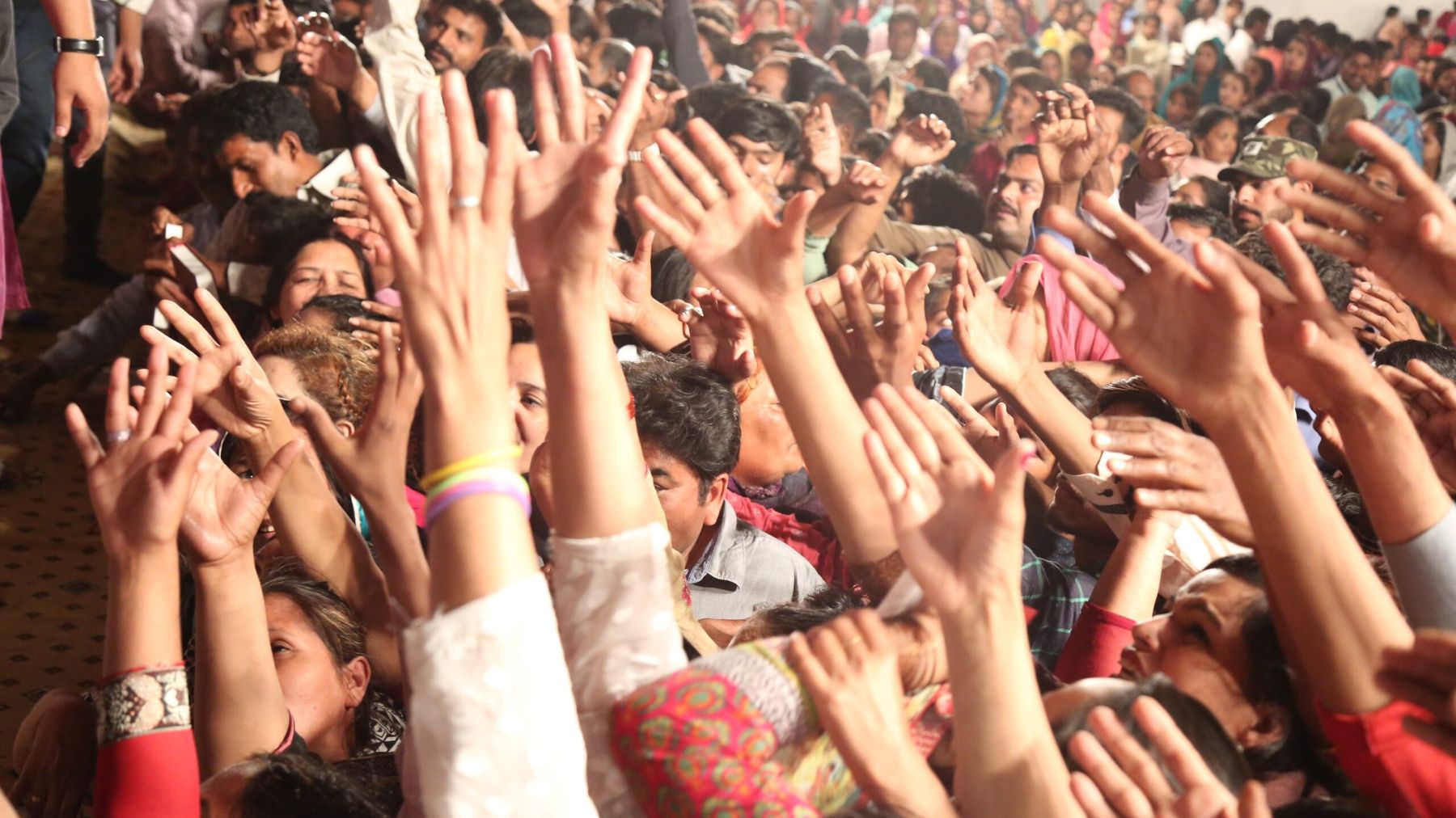 Hundreds of hands raised holding free Urdu Bibles at a crusade in Pakistan
