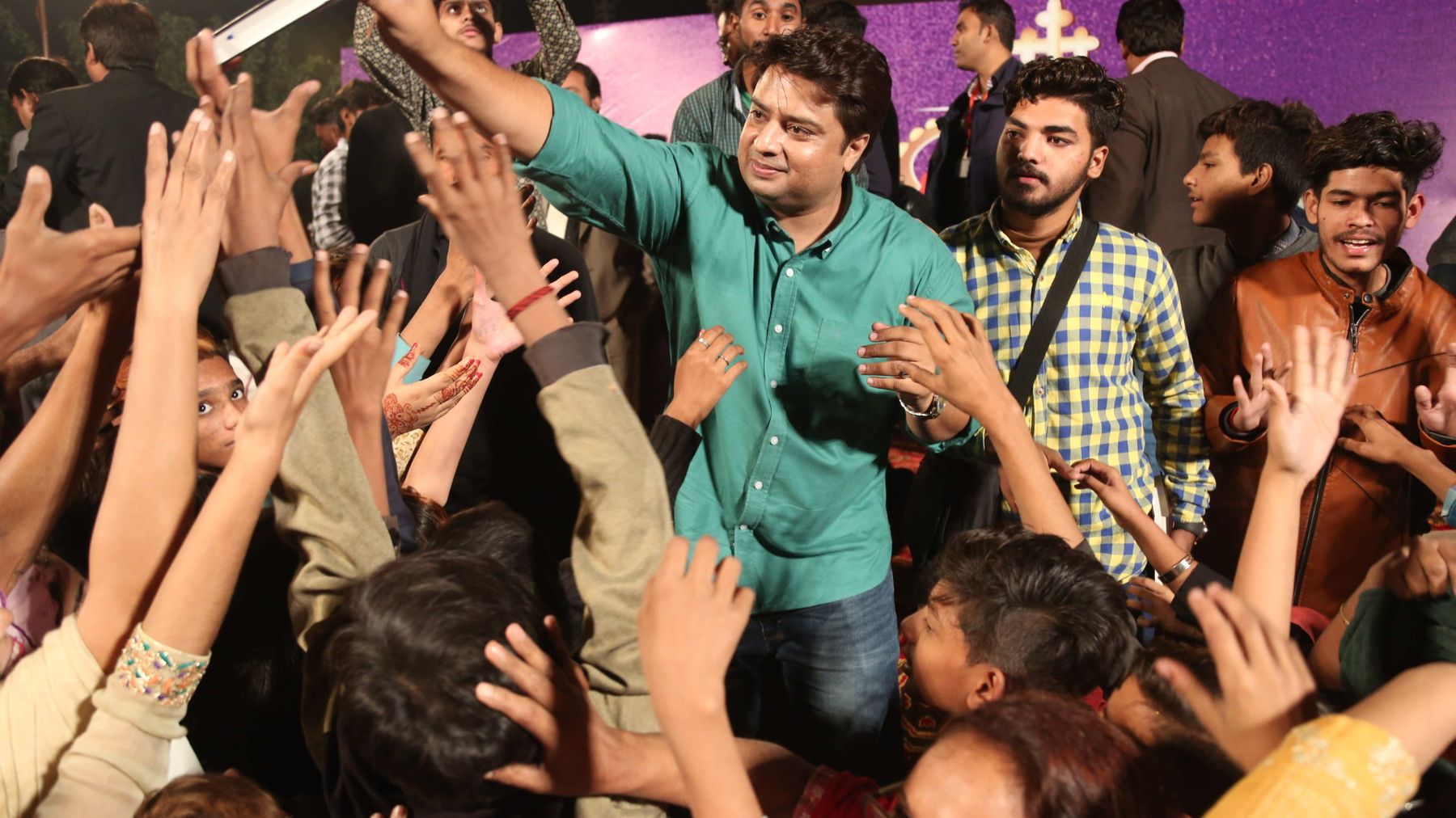 A crowd of believers in Pakistan reaching up to receive free Urdu Bibles