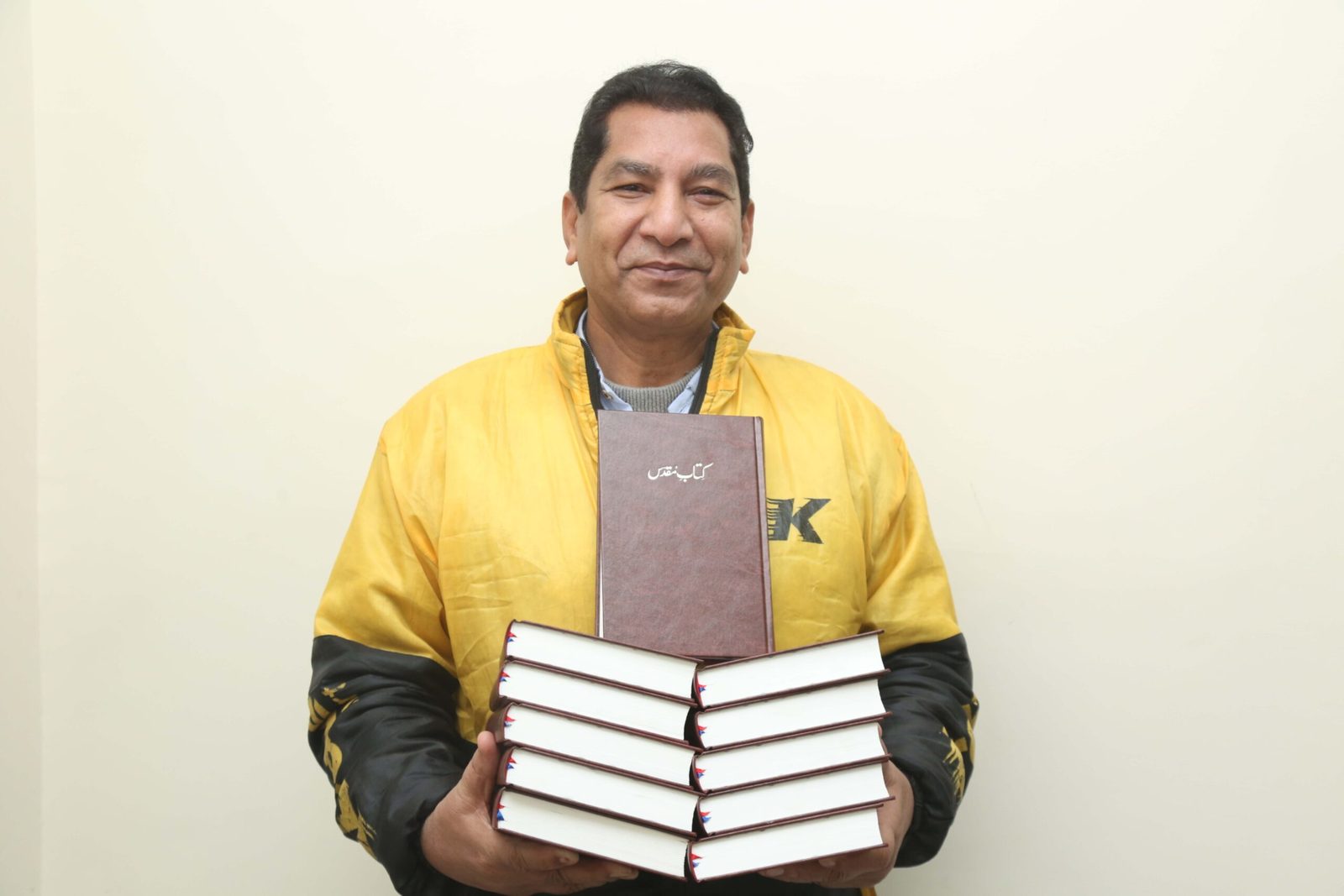 A Pakistani pastor holding a stack of free Urdu Bibles for his congregation