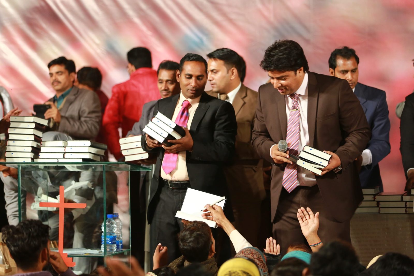 Pastors and church leaders receiving Urdu Bibles on stage at a Good Samaritan Ministries event in Pakistan