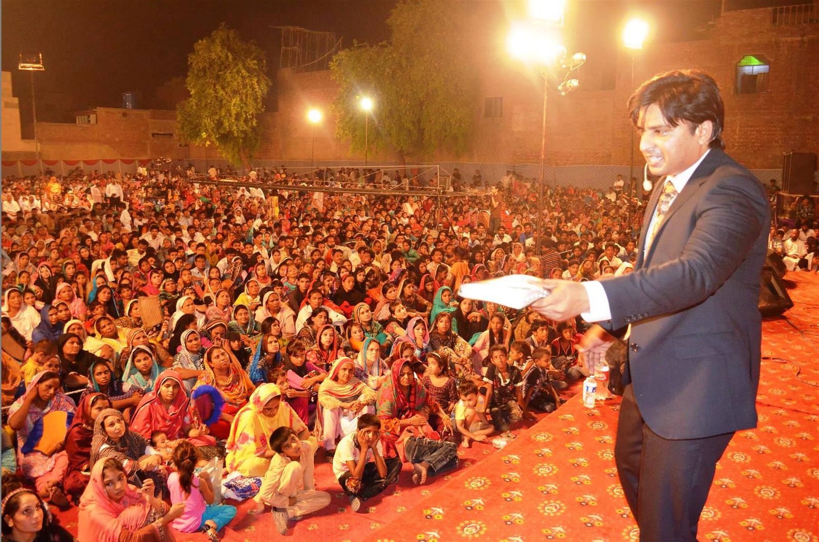 Rev. Dr. Naeem Nasir preaching to a large seated crowd at an open-air gospel meeting in Pakistan